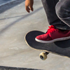 Skateboarder wearing red shoes performing trick on concrete ramp.