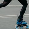 Close-up of a person skating fast on blue urban inline skates on city pavement.