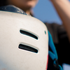 Person holding white skate helmet outdoors, ready to skate.