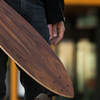 Skateboarder holding a longboard in an urban setting.